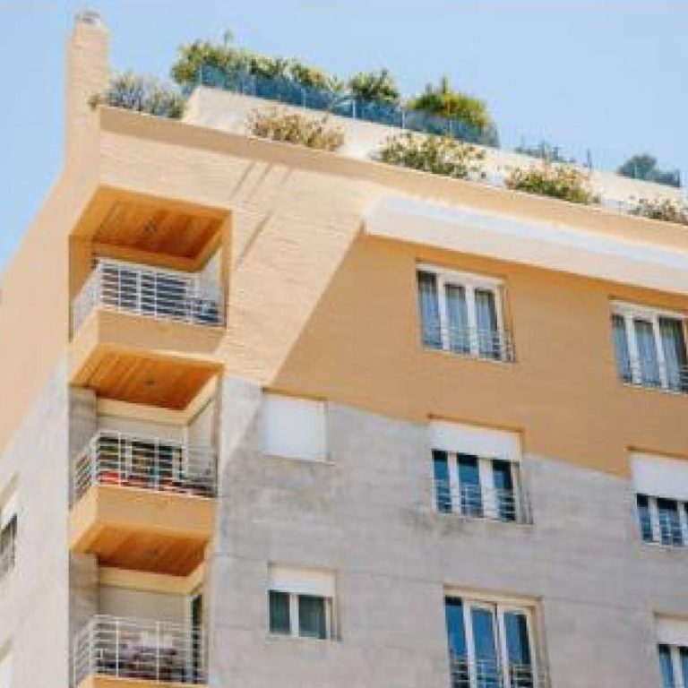 Immeuble moderne avec balcons et terrasse végétalisée.