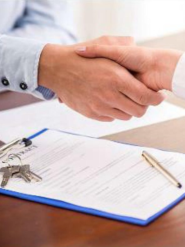 Poignée de main au-dessus d'un document et de clés sur une table.